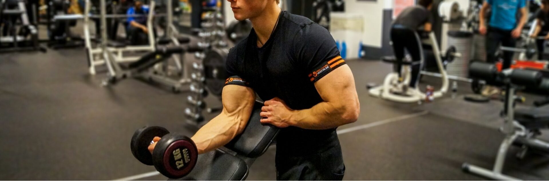 Mand træner biceps med okklusionsbånd fra Okklusionsudstyr.dk monteret på armene